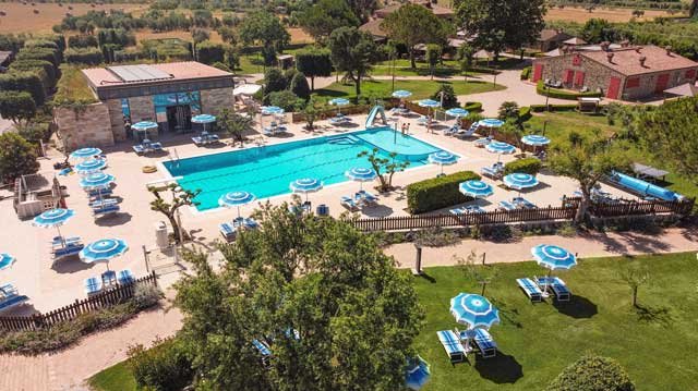 Piscina all'aperto con lettini e ombrelloni blu.