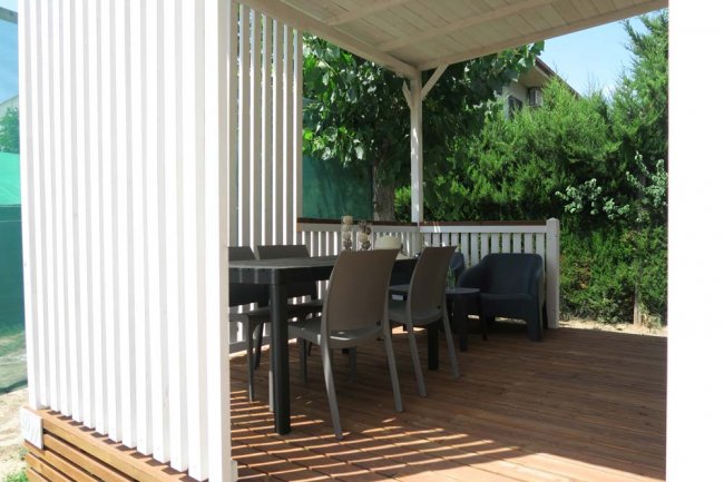 Gazebo bianco con tavolo e sedie su pavimento in legno.