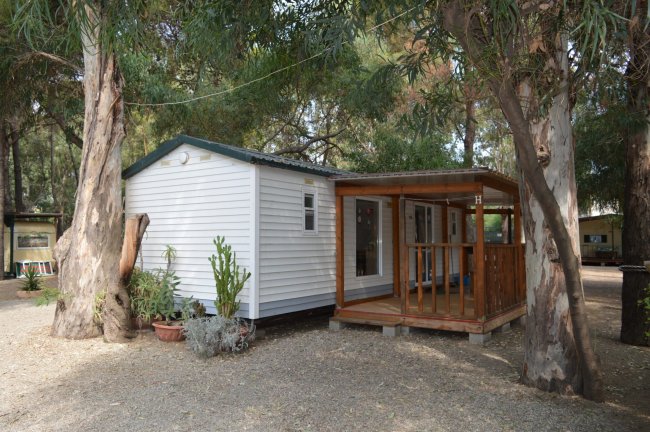 Casa mobile tra alberi con veranda in legno.