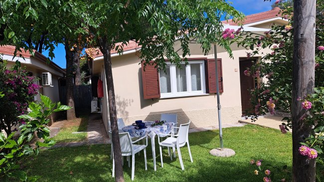 Casetta con giardino fiorito e tavolo da pranzo bianco all'aperto.