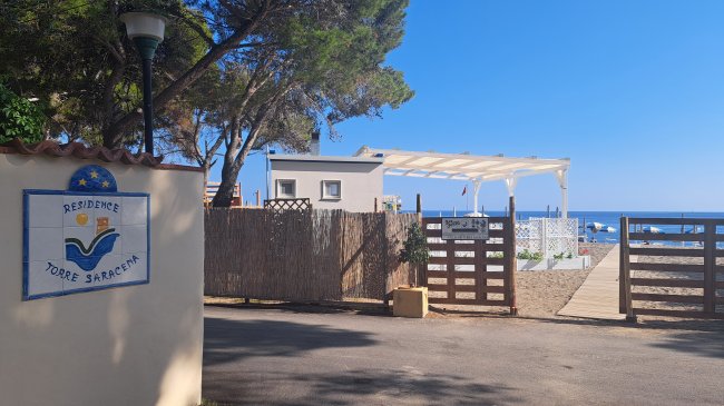 Ingresso del residence con vista sul mare e un cartello che dice