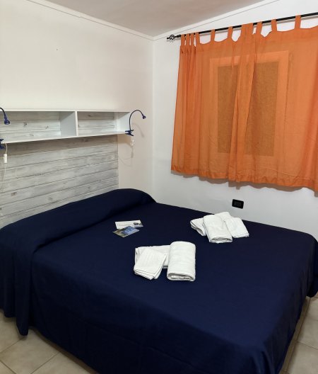 Camera da letto con lenzuola blu e tende arancioni.