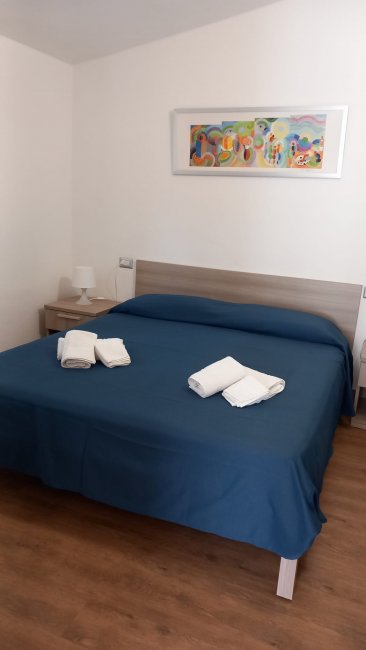 Camera da letto con letto matrimoniale e lenzuola blu.