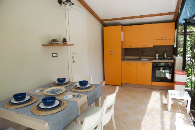 Cucina moderna con mobili arancioni, tavolo apparecchiato con stoviglie blu.