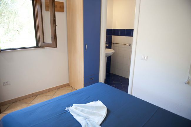 Camera da letto con letto blu e armadio. Bagno visibile.