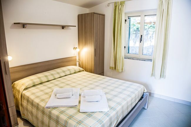 Camera da letto con letto matrimoniale, lenzuola a quadri e due asciugamani piegati.