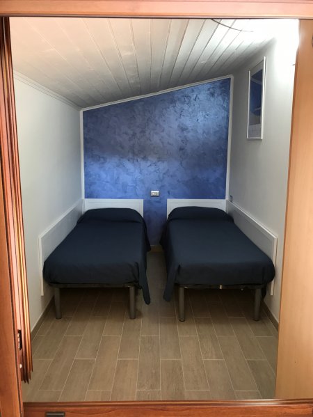 Due letti singoli con coperte blu, parete decorata in blu nella camera.