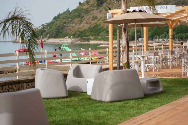 Giardino con sedie e ombrelloni vicino alla spiaggia.