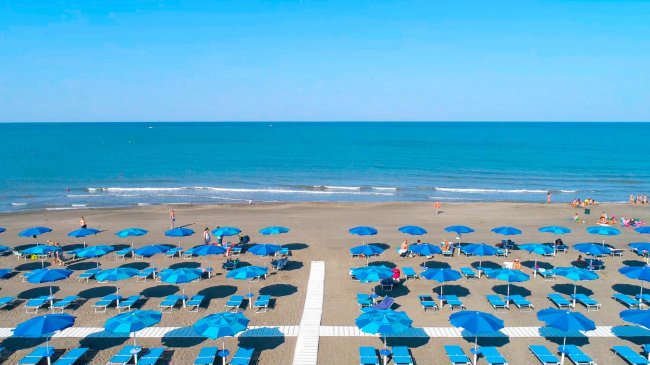 Spiaggia con ombrelloni blu allineati.