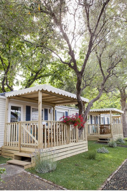 Casette in legno con porticato tra alberi.