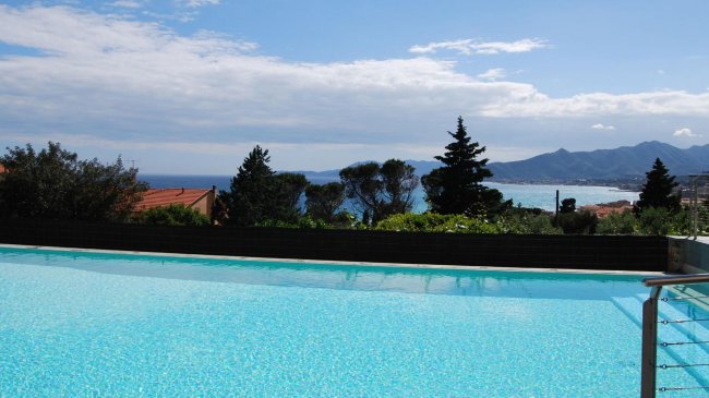 Piscina con vista sul mare e monti in lontananza.