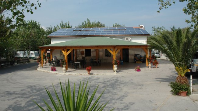 Edificio con veranda, tavoli all'aperto e pannelli solari sul tetto.