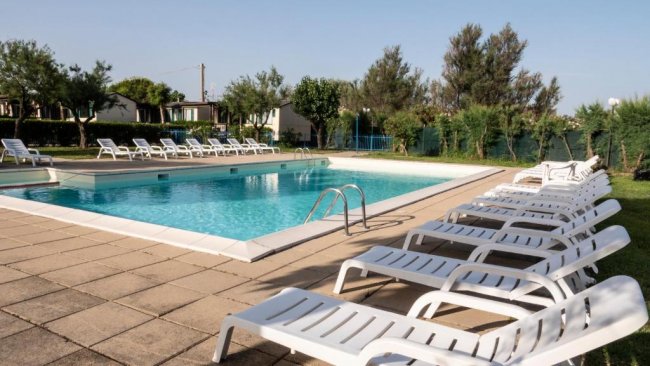 Piscina all'aperto con lettini bianchi.