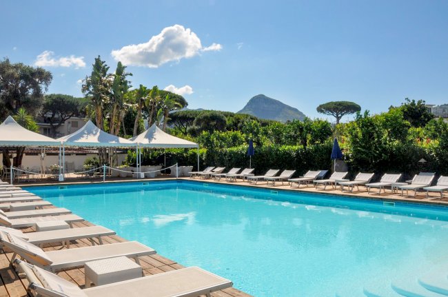 Piscina con lettini e montagne sullo sfondo.