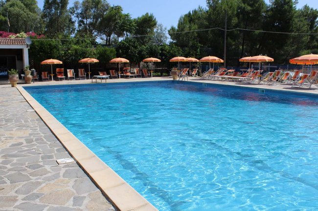 Piscina azzurra con lettini e ombrelloni arancioni.