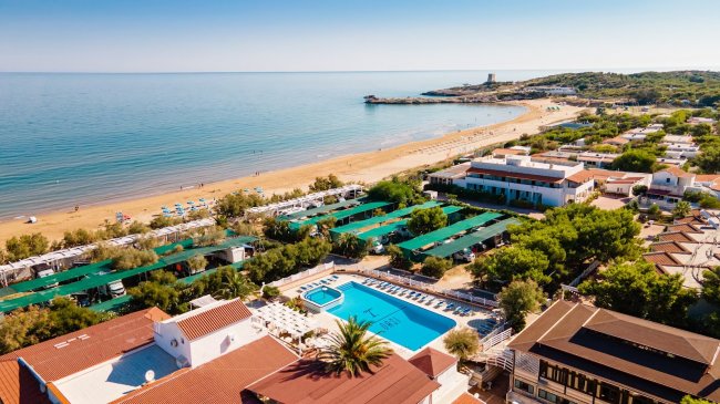 Vista aerea di un resort con piscina e spiaggia.
