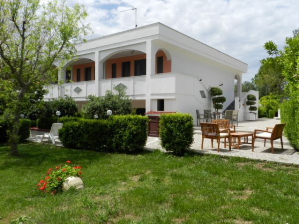 Casa bianca a due piani con giardino e mobili da esterno.