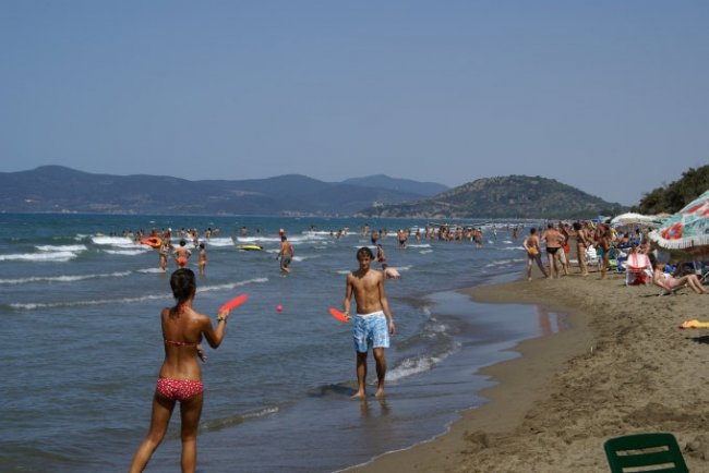 Persone giocano a frisbee su una spiaggia affollata.