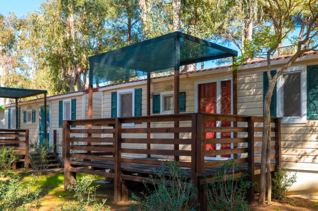 Bungalow con veranda in legno sotto alberi.