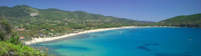 Spiaggia con mare azzurro e colline verdi.