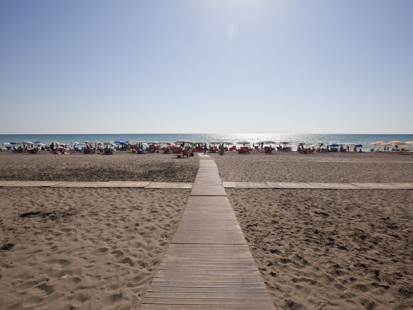 Spiaggia con passerella in legno e ombrelloni colorati.