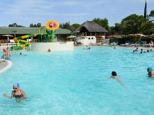 Piscina con scivoli, bambini e una decorazione a fiore.