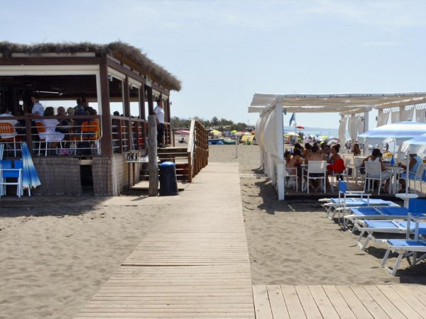 Spiaggia con passerella e ristoranti all'aperto.