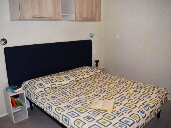 Letto matrimoniale con copriletto geometrico.