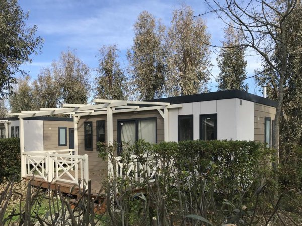 Casetta prefabbricata con veranda immersa nel verde.