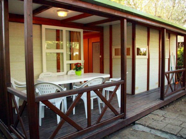 Veranda di legno con tavolo e sedie bianche.