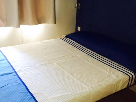 Letto matrimoniale con lenzuola bianche e blu.