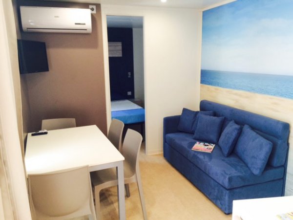 Soggiorno con divano blu, tavolo e aria condizionata.
