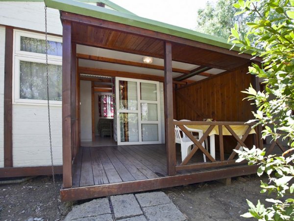 Veranda in legno con tavolo e sedie bianche.