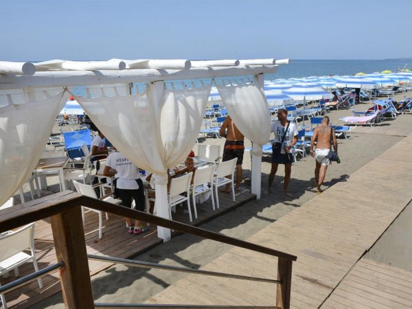 Spiaggia con gazebo, sedie e lettini.