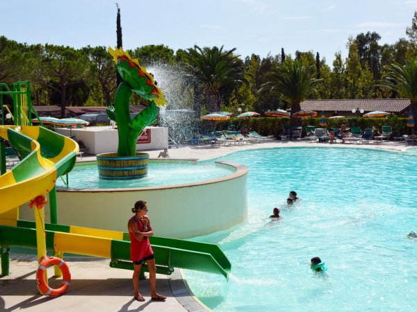 Scivolo giallo accanto a piscina, sole e spruzzi d'acqua.