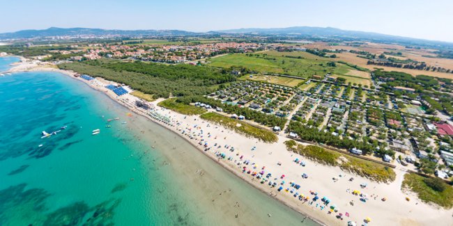 Spiaggia affollata vista dall'alto con acqua trasparente.