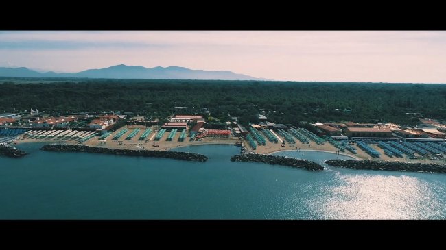 Vista aerea di uno stabilimento balneare con ombrelloni e il mare.