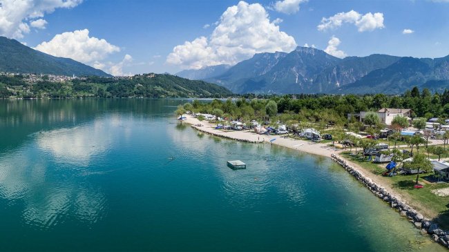 Spiaggia su un lago circondato da montagne verdi.