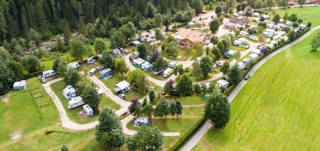 Vista aerea di un campeggio con camper e alberi.