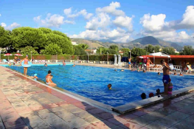 Piscina all'aperto con persone che nuotano.