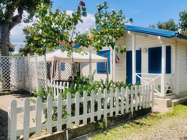 Casetta bianca con giardino e recinzione bianca.