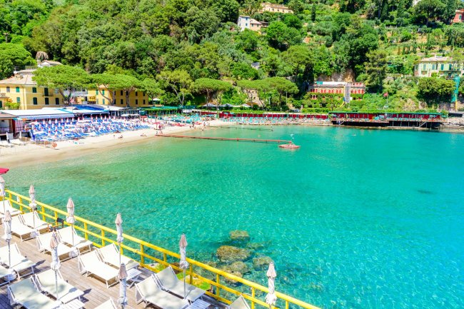 Spiaggia soleggiata con mare turchese e ombrelloni.