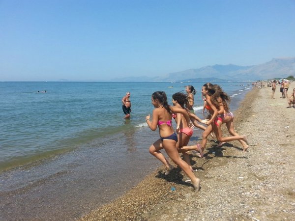 Bambini corrono verso il mare su una spiaggia.