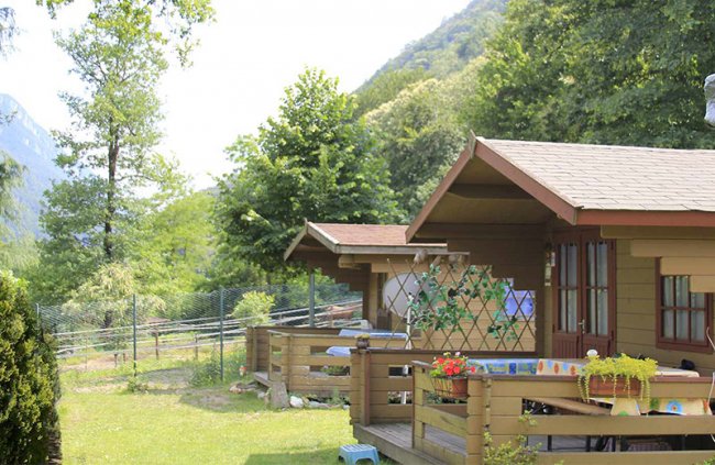 Una casa in legno circondata da alberi e prati verdi.