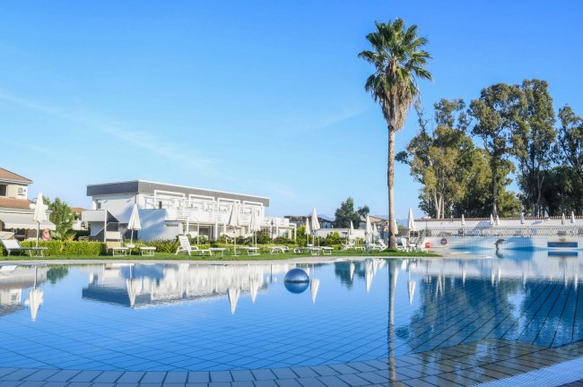 Piscina all'aperto con sdraio e palme.