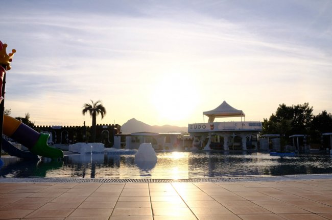Tramonto riflesso nella piscina con palme.