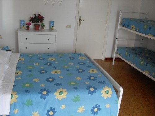 Camera con letto matrimoniale e letti a castello, coperte blu con fiori.