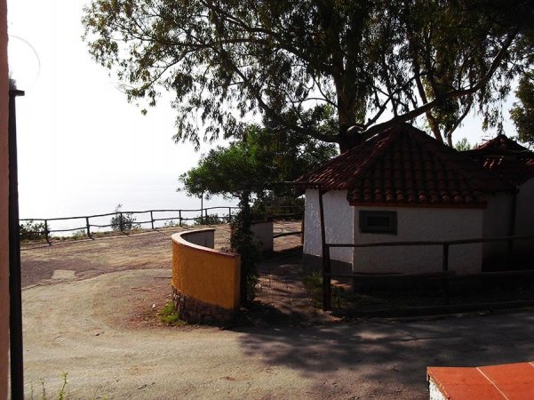 Edificio bianco con tetto a tegole rosse in un'area alberata.