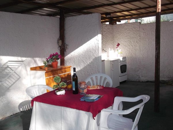 Una terrazza con tavolo apparecchiato, sedia di plastica, bottiglia di vino e pianta su mensola.