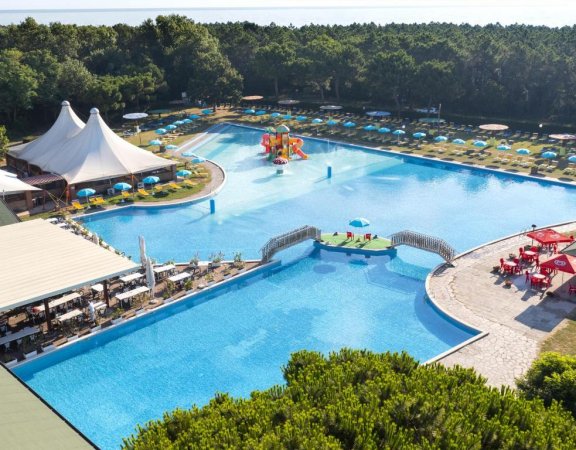 Grande piscina con area giochi e ombrelloni.
